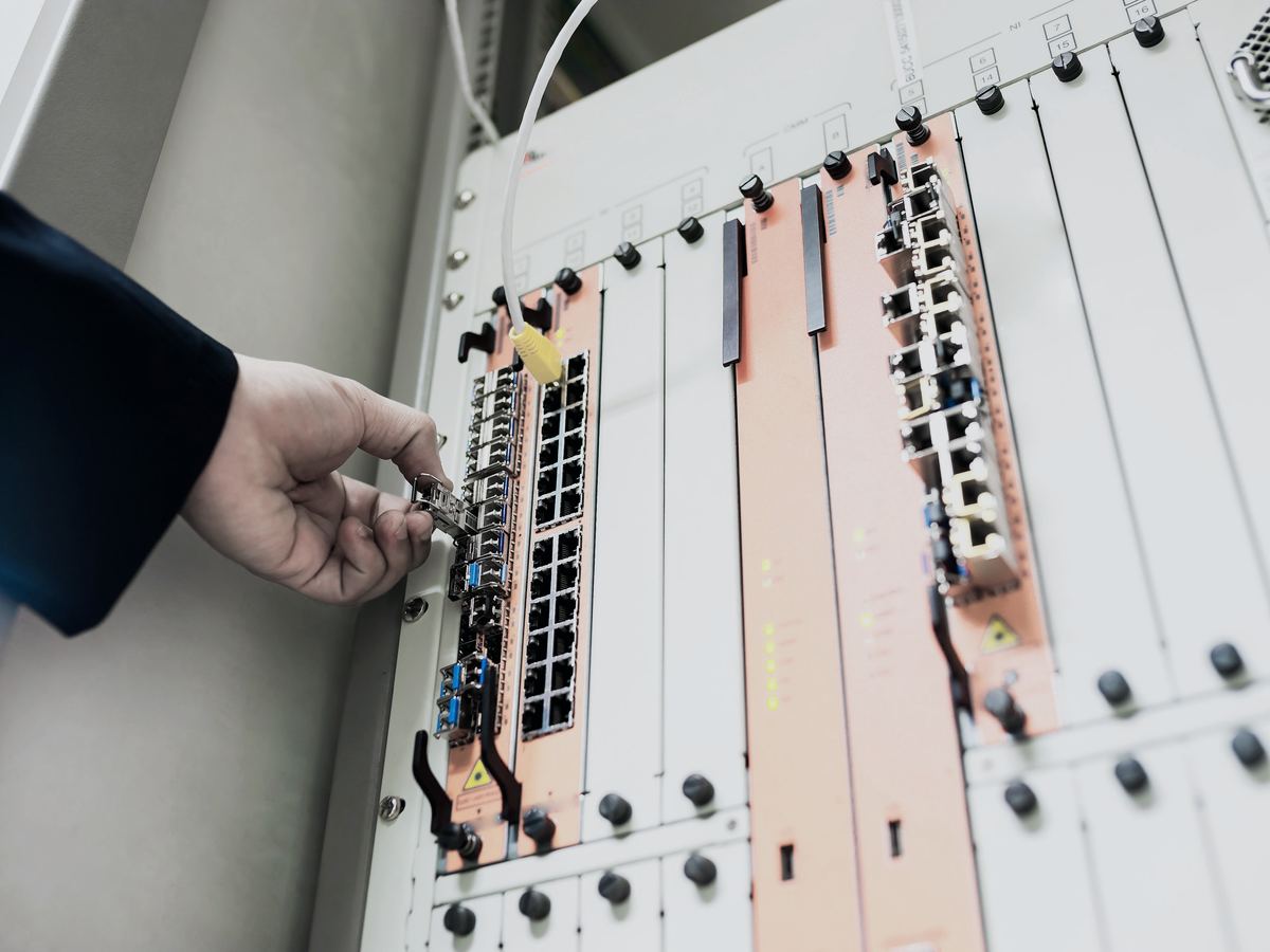Hand steckt ein SFP-Modul in einen Netzwerk-Switch